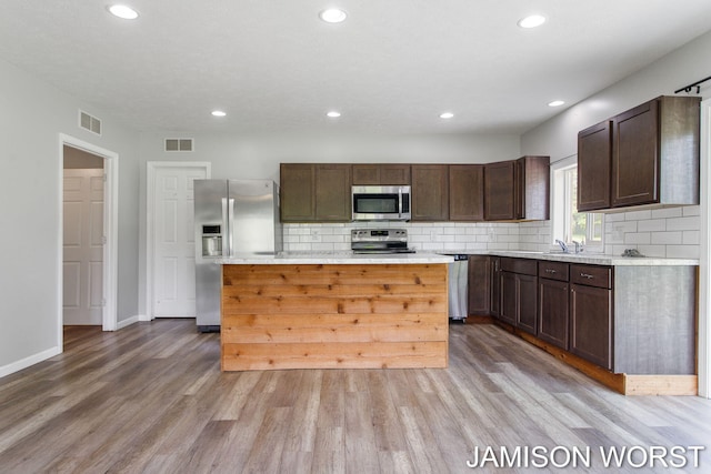 4403 4th St, Caledonia, MI 49316 - kitchen with appliances with stainless steel finishes, light wood-type flooring, decorative backsplash, dark brown cabinetry, and recessed lighting