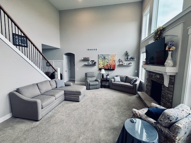 1692 Gloryfield Dr, Byron Center, MI 49315 - carpeted living room with a towering ceiling, arched walkways, a stone fireplace, stairs, and baseboards