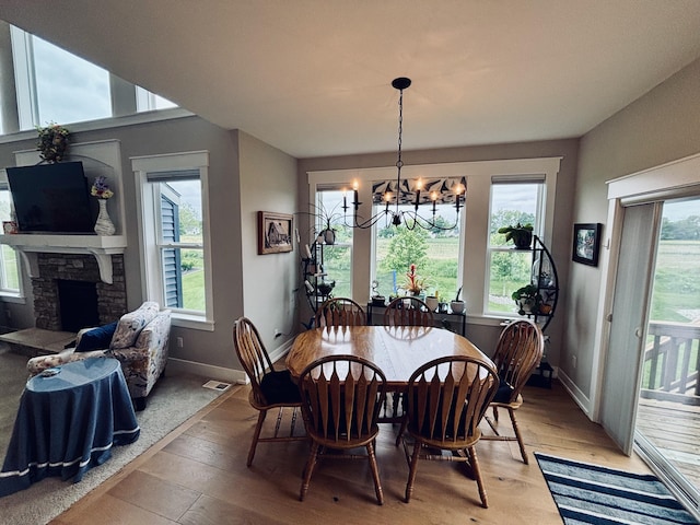 1692 Gloryfield Dr, Byron Center, MI 49315 - dining space featuring a chandelier, plenty of natural light, light wood-style flooring, and a stone fireplace