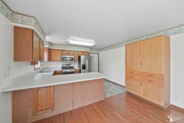 214 Roosevelt St, Dundee, MI 48131 - kitchen with appliances with stainless steel finishes, a sink, light countertops, light wood-style floors, and a peninsula