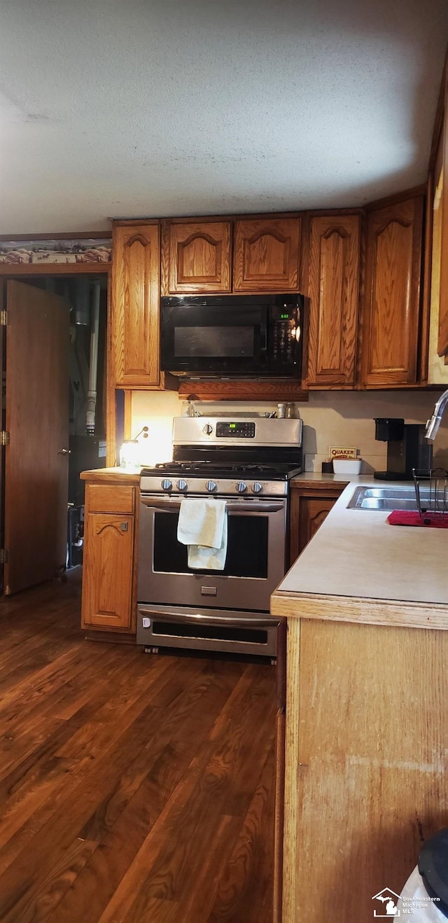 9361 Exeter Rd, Carleton, MI 48117 - kitchen with black microwave, stainless steel gas range oven, a sink, and brown cabinetry