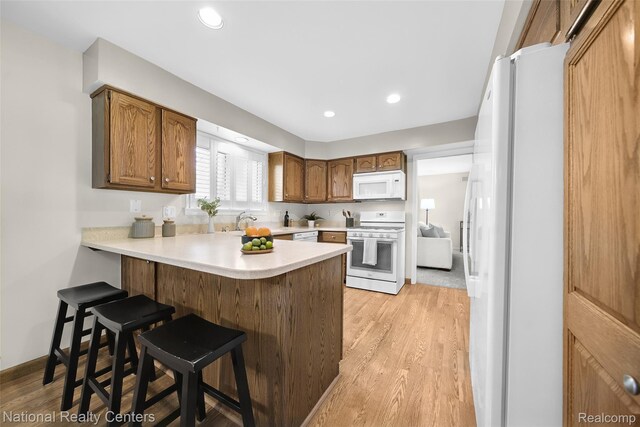 892 Hemlock Ct, Rochester, MI 48307 - kitchen featuring white appliances, a peninsula, a kitchen bar, light wood finished floors, and recessed lighting