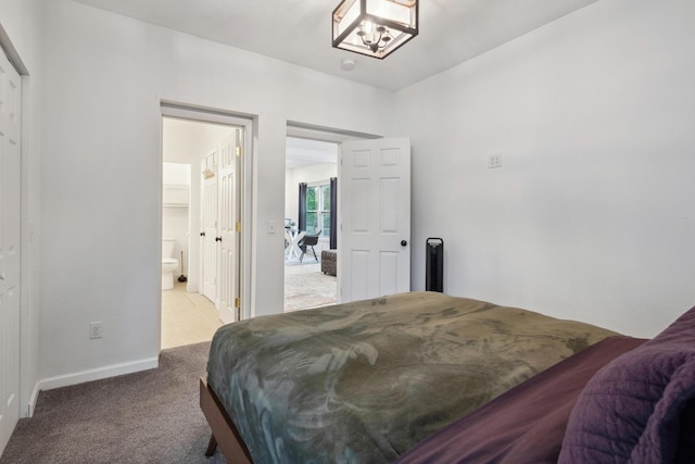 1645 College Ave SE, Grand Rapids, MI 49507 - carpeted bedroom featuring baseboards, connected bathroom, and a chandelier