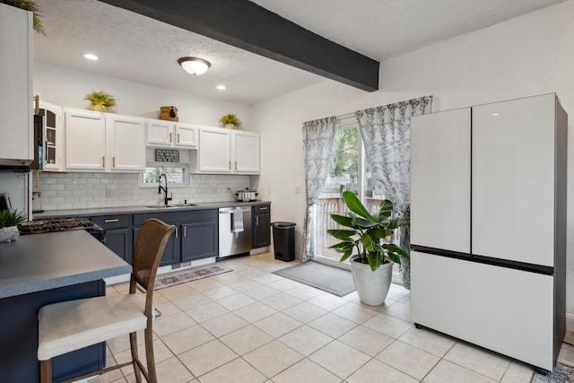 1645 College Ave SE, Grand Rapids, MI 49507 - kitchen featuring a sink, dishwasher, freestanding refrigerator, white cabinets, and backsplash