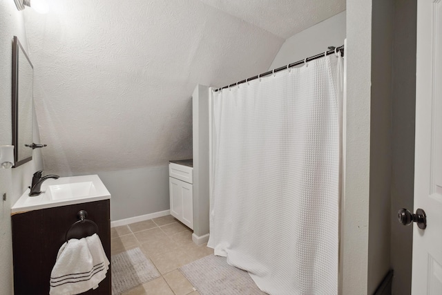 1645 College Ave SE, Grand Rapids, MI 49507 - bathroom featuring vaulted ceiling, vanity, a textured ceiling, tile patterned flooring, and baseboards