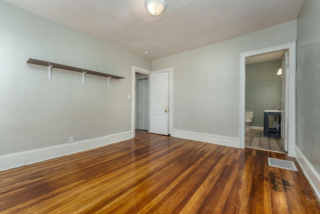 617 Wheaton Ave, Kalamazoo, MI 49008 - unfurnished bedroom with wood-type flooring, ensuite bathroom, baseboards, and a wood stove