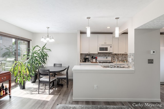 6387 Wainscot Dr SE Unit 102, Grand Rapids, MI 49546 - kitchen with white appliances, tasteful backsplash, light countertops, wood finished floors, and pendant lighting