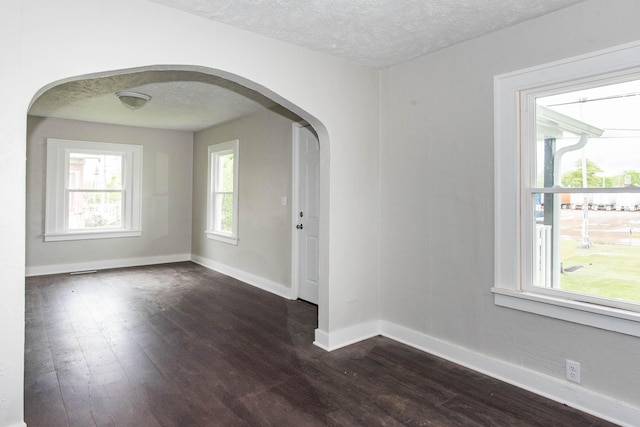 1226 Shakespeare Ave, Kalamazoo, MI 49001 - empty room with arched walkways, a textured ceiling, dark wood-style floors, and baseboards