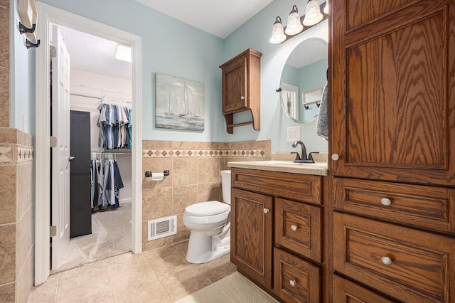 4465 Spinnaker Ln, Pleasant Lake, MI 49272 - bathroom with tile walls, vanity, tile patterned floors, a spacious closet, and a wainscoted wall