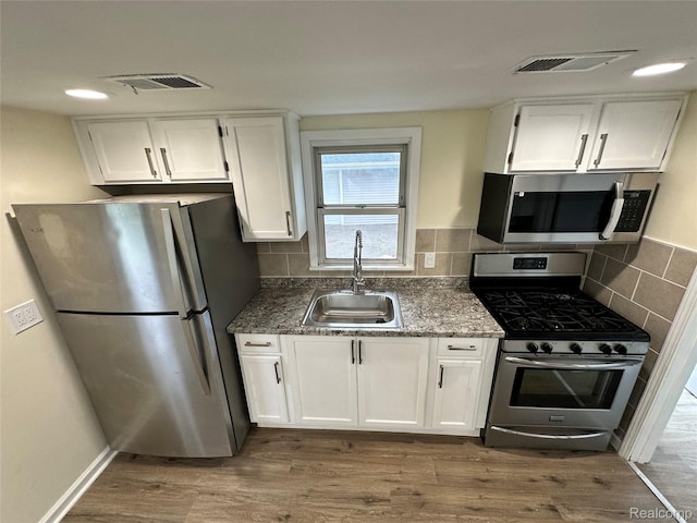 33050 John Hauk St, Garden City, MI 48135 - kitchen featuring stainless steel appliances, a sink, white cabinets, wood finished floors, and tasteful backsplash