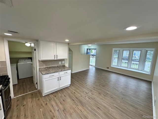 33050 John Hauk St, Garden City, MI 48135 - kitchen featuring washer / clothes dryer, stainless steel range with gas stovetop, light wood-style floors, white cabinetry, and dark stone countertops