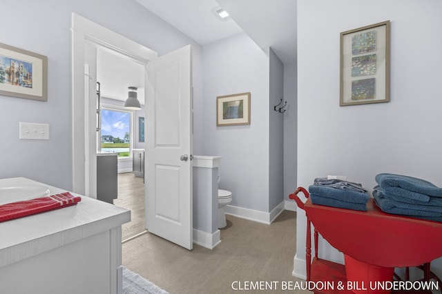 13944 Harrington Lndg, Holland, MI 49424 - bathroom featuring toilet, vanity, baseboards, and wood finished floors