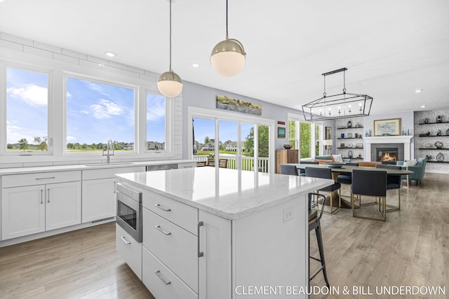 13944 Harrington Lndg, Holland, MI 49424 - kitchen with a sink, stainless steel appliances, a center island, white cabinetry, and light wood-type flooring