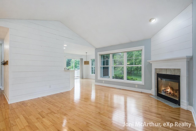 13 Foleys Grade, Lowell, MI 49331 - unfurnished living room featuring a tile fireplace, vaulted ceiling, light wood finished floors, and wooden walls
