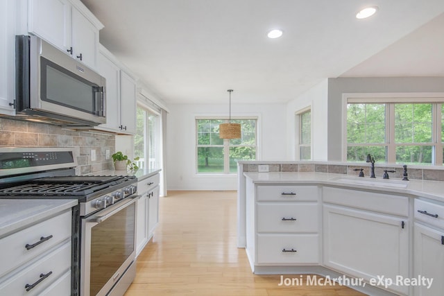 13 Foleys Grade, Lowell, MI 49331 - kitchen with appliances with stainless steel finishes, light countertops, decorative backsplash, light wood-style floors, and white cabinets