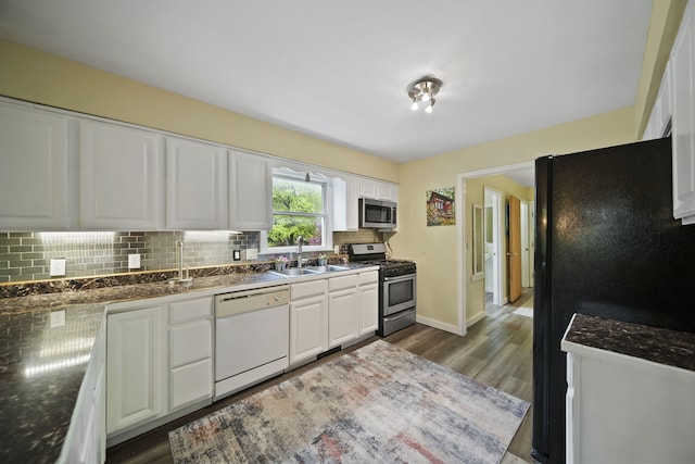 9428 Talladay Rd, Willis, MI 48191 - kitchen with stainless steel appliances, a sink, decorative backsplash, white cabinetry, and dark wood-style flooring