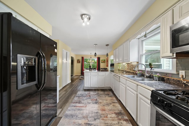 9428 Talladay Rd, Willis, MI 48191 - kitchen with appliances with stainless steel finishes, a peninsula, a sink, and tasteful backsplash