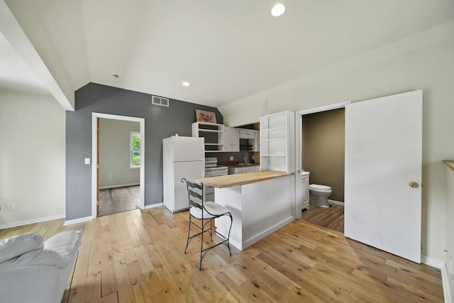 9428 Talladay Rd, Willis, MI 48191 - kitchen with wooden counters, white appliances, vaulted ceiling, open shelves, and light wood-style floors