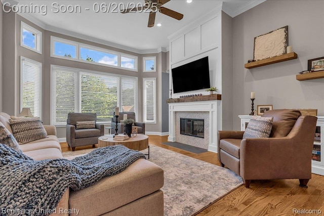 22858 Saint George Cir S, Lyon, MI 48178 - living room featuring ceiling fan, ornamental molding, a fireplace with flush hearth, light wood-type flooring, and recessed lighting
