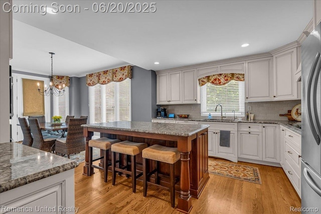 22858 Saint George Cir S, Lyon, MI 48178 - kitchen featuring a chandelier, light wood-style floors, tasteful backsplash, a kitchen breakfast bar, and recessed lighting