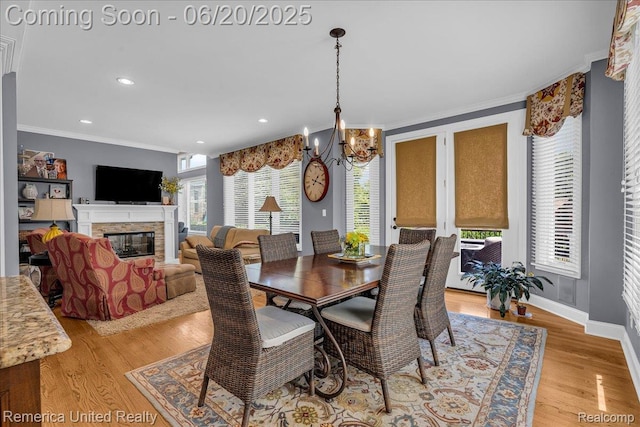 22858 Saint George Cir S, Lyon, MI 48178 - dining area featuring ornamental molding, a chandelier, a glass covered fireplace, light wood finished floors, and recessed lighting