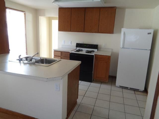 1020 S Lansing, Mount Pleasant, MI 48858 - kitchen with freestanding refrigerator, a sink, range, light countertops, and light tile patterned flooring