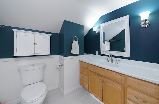 2720 Willa Dr, Saint Joseph, MI 49085 - bathroom with wainscoting, toilet, vanity, vaulted ceiling, and tile patterned flooring