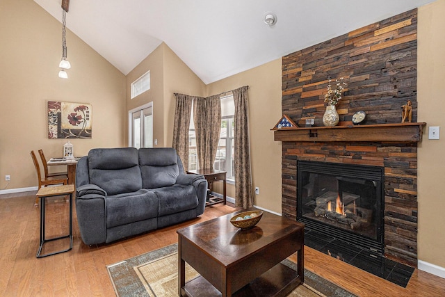 764 Allen Rd, Milan, MI 48160 - living area featuring wood finished floors, baseboards, a stone fireplace, and high vaulted ceiling