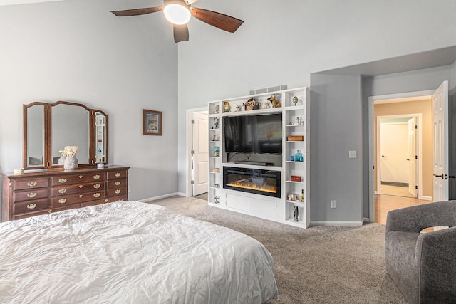 764 Allen Rd, Milan, MI 48160 - carpeted bedroom with baseboards, a towering ceiling, ceiling fan, and a glass covered fireplace