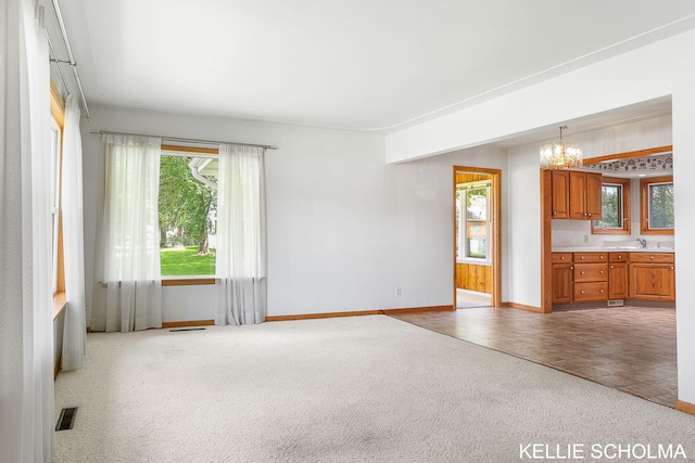 226 Palms St SW, Grand Rapids, MI 49548 - unfurnished living room featuring a chandelier, baseboards, plenty of natural light, and carpet flooring