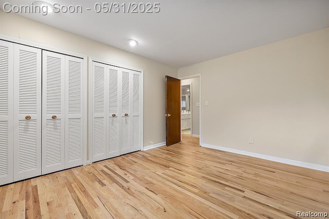 4041 W Maple Rd Apt 204, Bloomfield Hills, MI 48301 - unfurnished bedroom with two closets, baseboards, and light wood finished floors