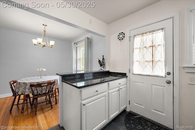 731 N Eton St, Birmingham, MI 48009 - kitchen with a peninsula, a chandelier, dark wood-type flooring, white cabinets, and pendant lighting