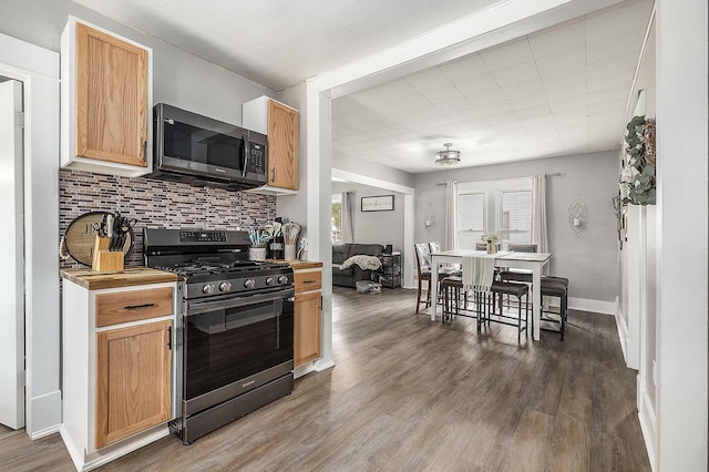 49 S Arthur St, Grant, MI 49327 - kitchen with stainless steel gas stove, decorative backsplash, wood finished floors, and baseboards