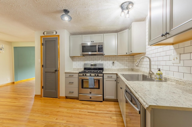6210 Johnson Rd, Coloma, MI 49038 - kitchen with stainless steel appliances, a sink, light wood-style flooring, decorative backsplash, and a textured ceiling
