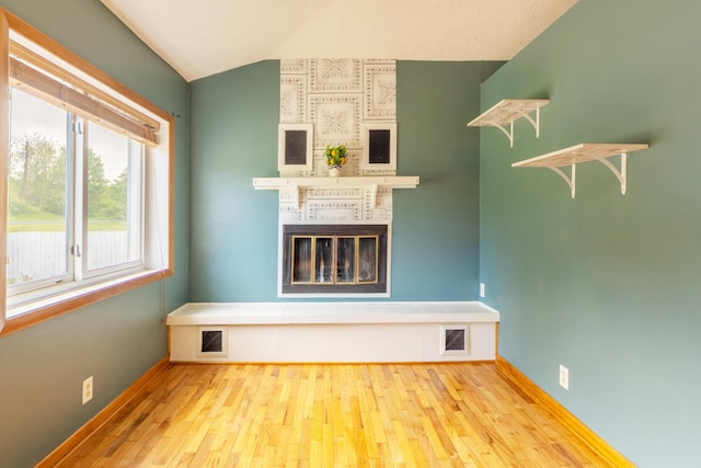 6210 Johnson Rd, Coloma, MI 49038 - unfurnished living room featuring wood finished floors, a tiled fireplace, vaulted ceiling, and baseboards