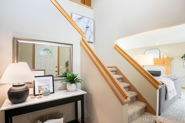 5540 Koster Dr SW, Wyoming, MI 49418 - stairway featuring a tiled fireplace, a towering ceiling, and carpet floors