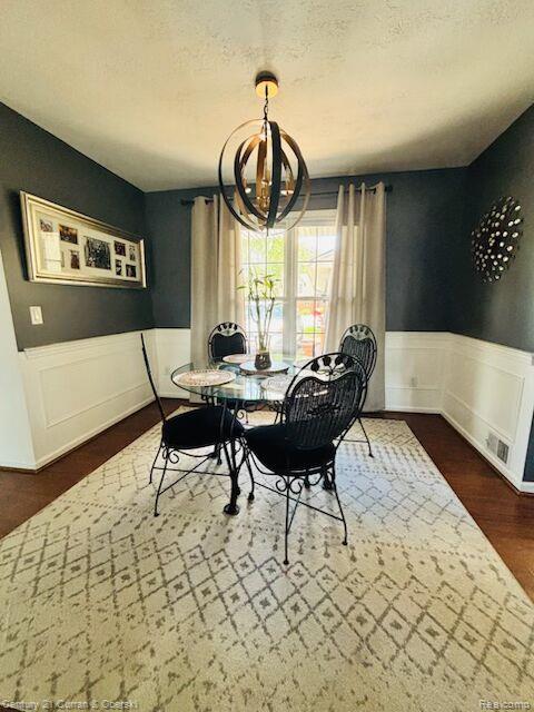 45215 Custer Ave, Utica, MI 48317 - dining area featuring a wainscoted wall, a chandelier, a textured ceiling, and dark wood-style flooring