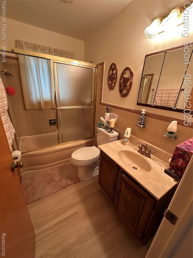 35951 Dover St, Livonia, MI 48150 - bathroom featuring wood finished floors, vanity, toilet, combined bath / shower with glass door, and tile walls