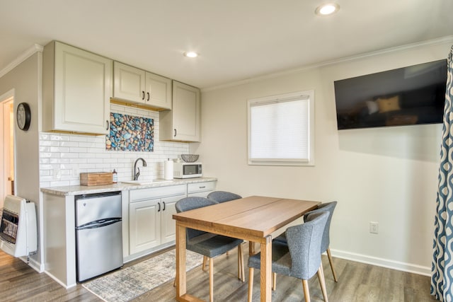 6132 W Houghton Lake Dr, Houghton Lake, MI 48629 - kitchen featuring freestanding refrigerator, white microwave, heating unit, a sink, and light wood-style flooring