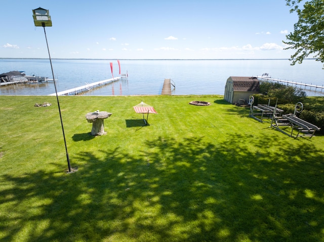 6132 W Houghton Lake Dr, Houghton Lake, MI 48629 - view of green lawn featuring a fire pit, a water view, and a boat dock