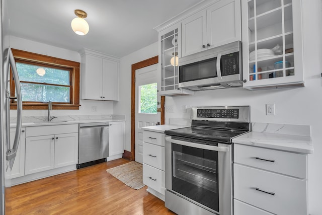 710 S 1st St, Ann Arbor, MI 48103 - kitchen with appliances with stainless steel finishes, a sink, white cabinetry, light wood-style floors, and glass insert cabinets