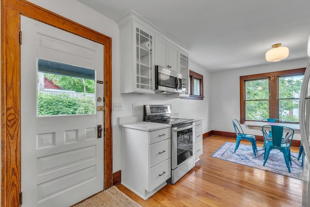 710 S 1st St, Ann Arbor, MI 48103 - kitchen with stainless steel appliances, baseboards, light countertops, light wood-style flooring, and glass insert cabinets