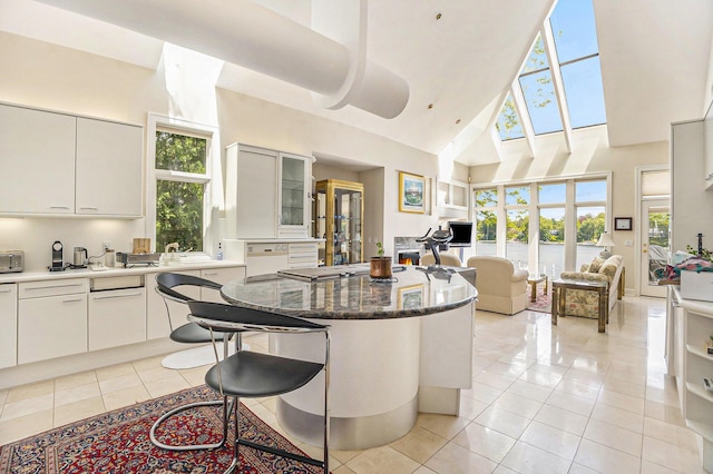 15919 Orchard Point Dr, Spring Lake, MI 49456 - kitchen featuring high vaulted ceiling, open floor plan, light tile patterned floors, a breakfast bar area, and a kitchen island