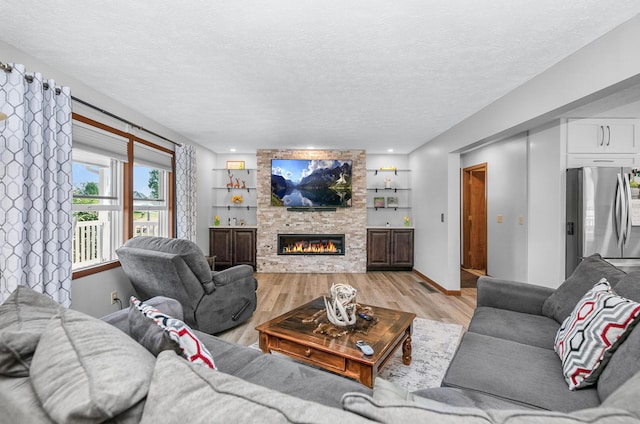 13881 Rivercrest Dr, White Pigeon, MI 49099 - living area featuring light wood-style floors, a textured ceiling, a fireplace, and baseboards