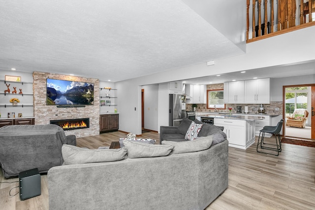 13881 Rivercrest Dr, White Pigeon, MI 49099 - living room with a fireplace, light wood-style flooring, a textured ceiling, and recessed lighting