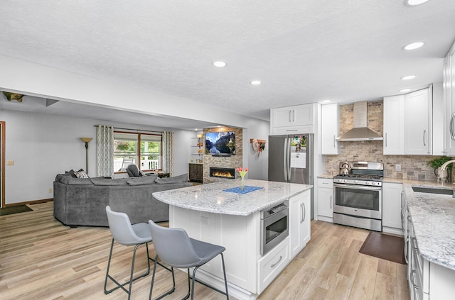 13881 Rivercrest Dr, White Pigeon, MI 49099 - kitchen featuring stainless steel appliances, wall chimney range hood, open floor plan, a sink, and a kitchen island