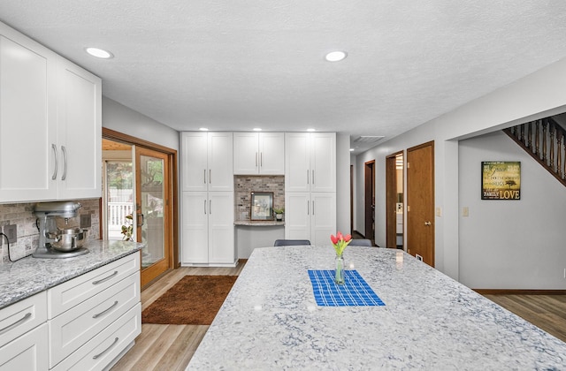13881 Rivercrest Dr, White Pigeon, MI 49099 - kitchen featuring wood finished floors, backsplash, white cabinets, light stone countertops, and a textured ceiling