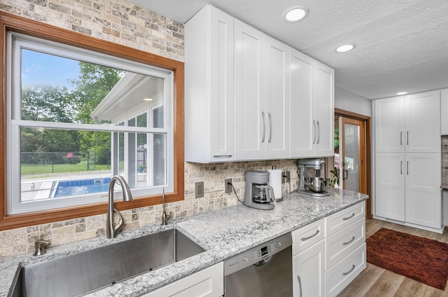 13881 Rivercrest Dr, White Pigeon, MI 49099 - kitchen featuring a sink, stainless steel dishwasher, wood finished floors, white cabinetry, and a textured ceiling