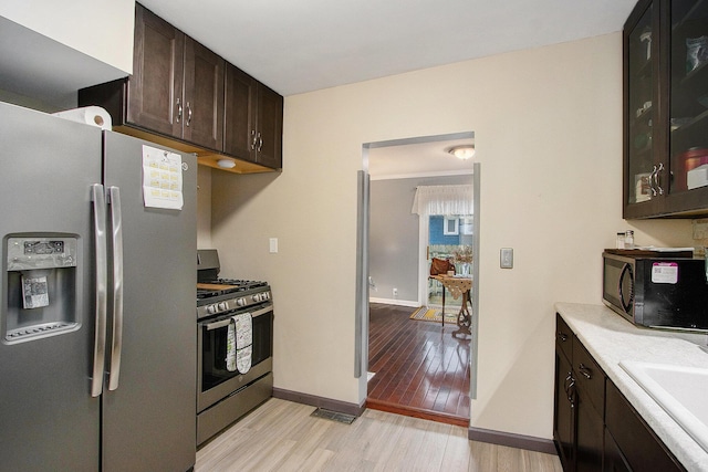 10933 Portage Rd, Portage, MI 49002 - kitchen with appliances with stainless steel finishes, light wood-style flooring, light countertops, dark brown cabinetry, and a sink