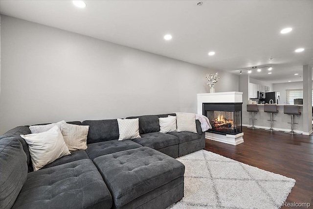 3070 Camden Dr, Troy, MI 48084 - living room with dark wood-style floors, recessed lighting, a multi sided fireplace, and baseboards
